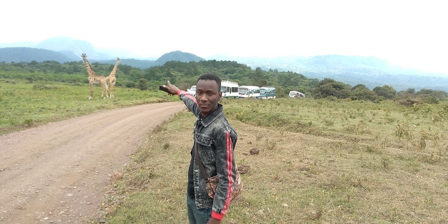 1st Year Student observing Giraffe and other animals found in the wooded grassland at Arusha National Park